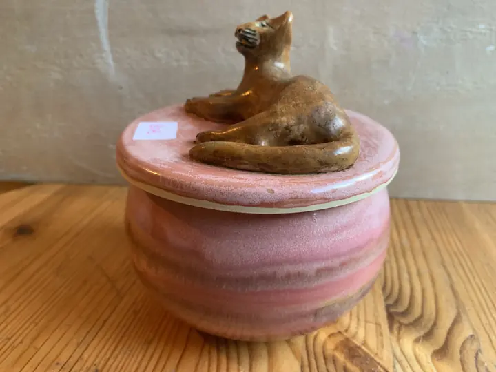 Boîte rose au couvercle surmonté d'un chat couché