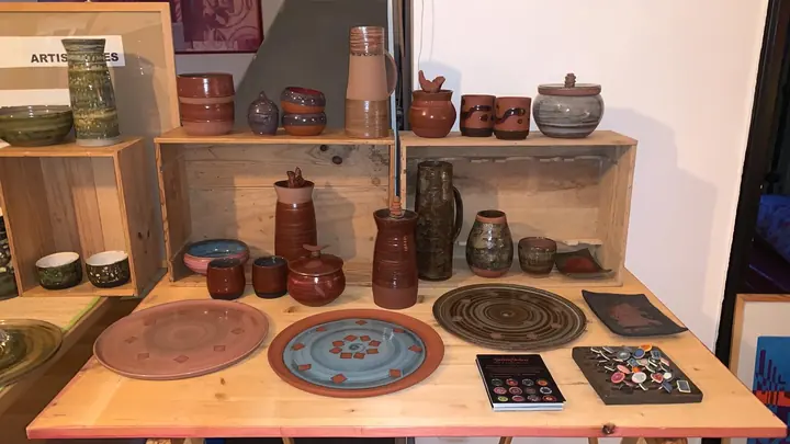 Étal en intérieur : plats, pichets et pots sur une table et des caisses en bois