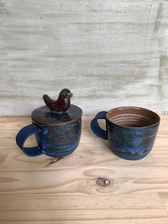 Deux tasses bleu nuit, l'une coiffée d'un couvercle à oiseau